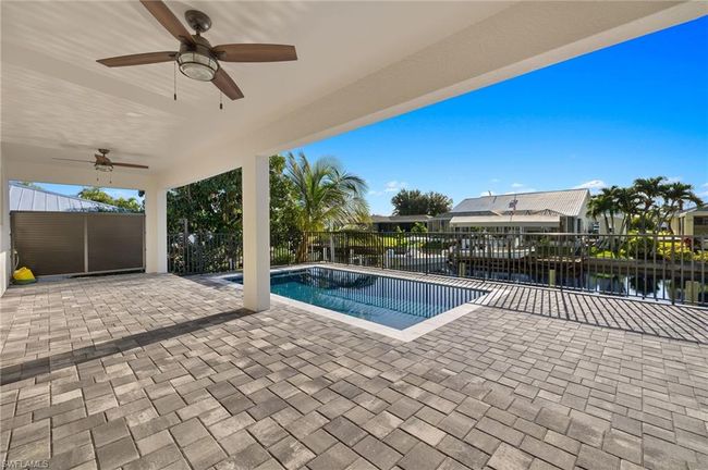View of swimming pool with a patio, a water view, and ceiling fan | Image 34