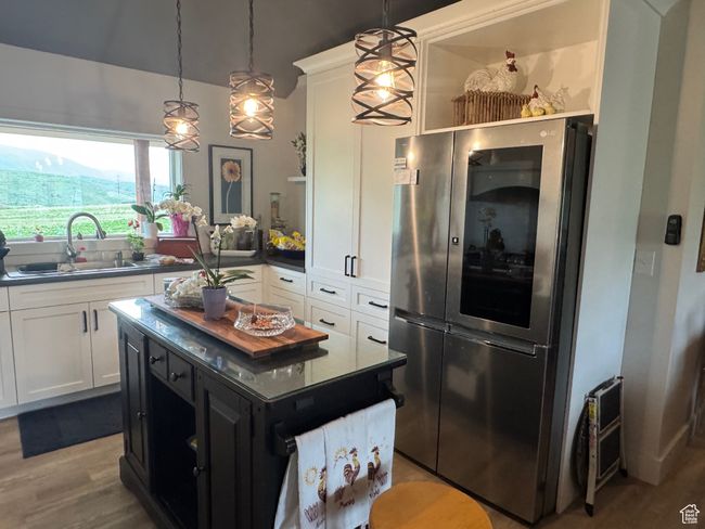 Kitchen featuring open shelves, a sink, white cabinets, and hanging light fixtures | Image 7