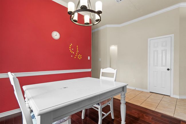 Dining area with a chandelier, crown molding, and wood finished floors | Image 9