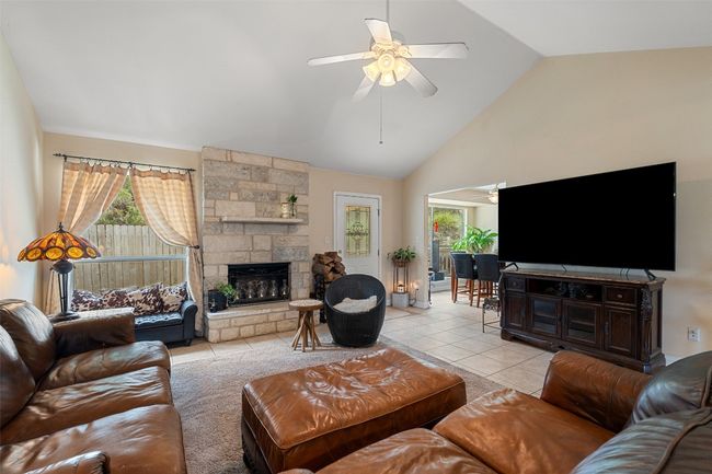 Living area with a ceiling fan, light tile patterned floors, a fireplace, and high vaulted ceiling | Image 9