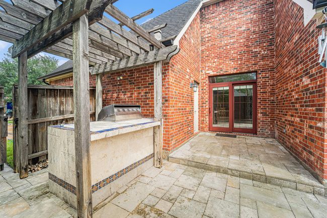 Fire up the grill and enjoy this built-in outdoor kitchen space, perfect for weekend barbecues and summer entertaining under the pergola. | Image 31