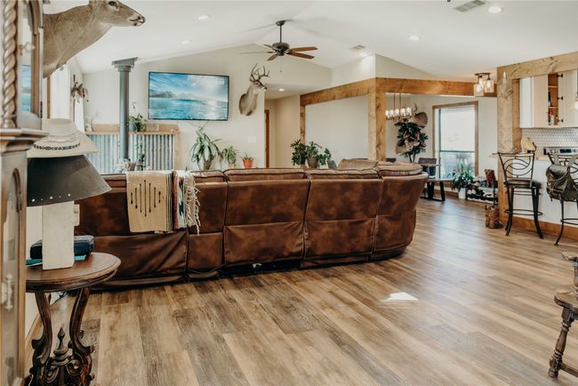Living room with ceiling fan, light wood-type flooring, lofted ceiling, ornate columns, and recessed lighting | Image 5