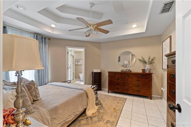 Bedroom featuring a raised ceiling, recessed lighting, light tile patterned floors, baseboards, and a ceiling fan | Image 18
