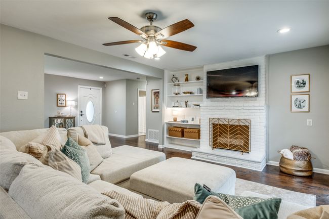 Living room featuring a ceiling fan, dark wood-style flooring, a brick fireplace, recessed lighting, and built in shelves | Image 13