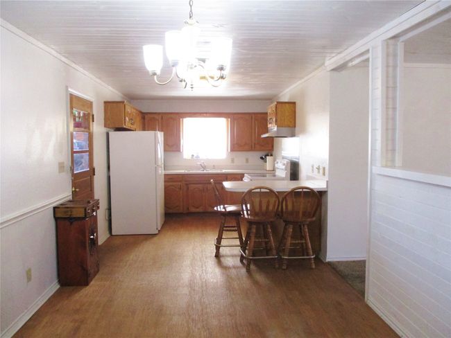 Kitchen with stove, wood finished floors, a sink, freestanding refrigerator, and brown cabinets | Image 10