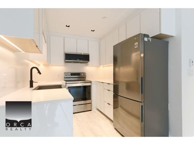 Kitchen featuring stainless steel appliances, extractor fan, white cabinetry, light countertops, and modern cabinets | Image 11