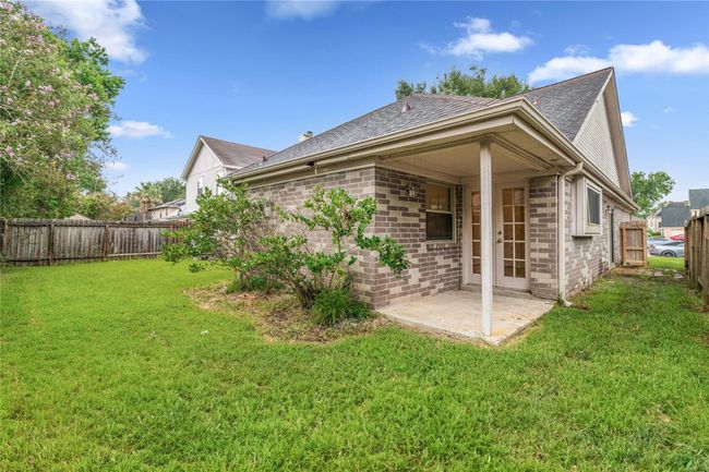 Covered patio with French doors extends living space into the backyard. | Image 24