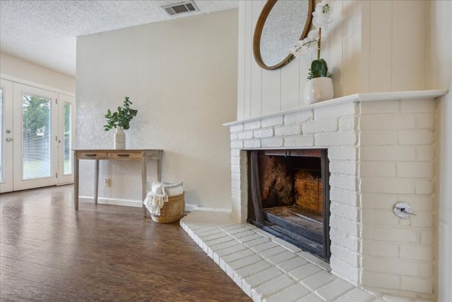 Unfurnished living room featuring a brick fireplace, wood finished floors, and a textured ceiling | Image 6