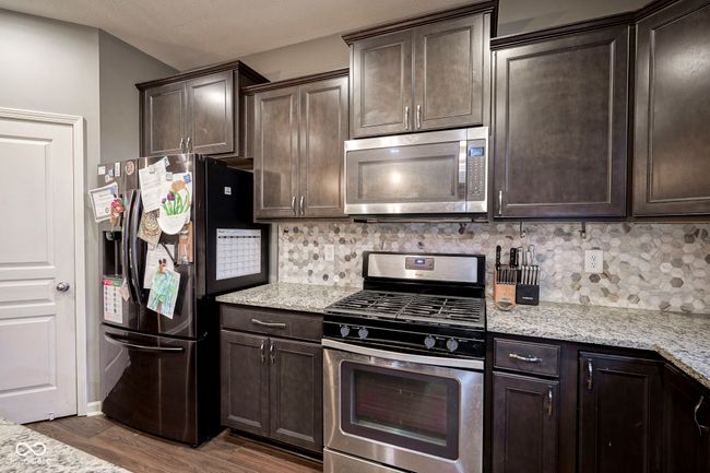 kitchen with stainless steel appliances, dark brown cabinetry, and decorative backsplash | Image 12