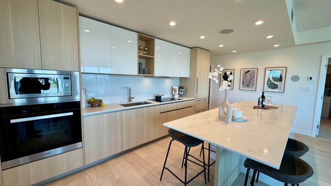 Kitchen featuring oven, a sink, stainless steel microwave, modern cabinets, and a breakfast bar area | Image 4