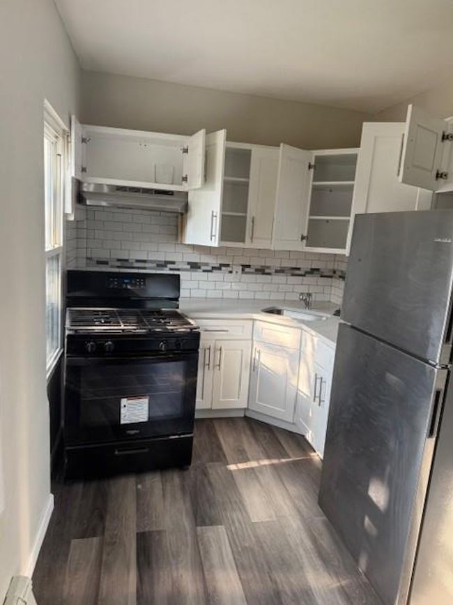Kitchen featuring fridge, open shelves, stove, exhaust hood, and dark wood-style flooring | Image 5