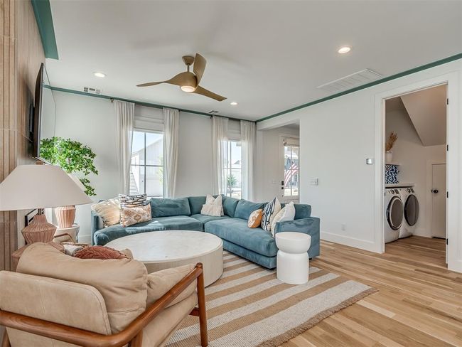 Living room with washer and dryer, a ceiling fan, light wood finished floors, baseboards, and recessed lighting | Image 9