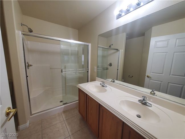 Bathroom with a stall shower, tile patterned floors, double vanity, and a sink | Image 13