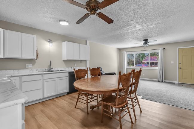 Dining space featuring a ceiling fan, a textured ceiling, and light wood-style floors | Image 12