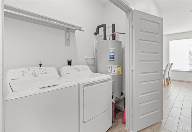 Laundry area featuring washing machine and clothes dryer, water heater, and light tile patterned flooring | Image 10