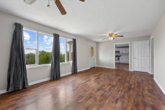 Unfurnished living room with a ceilingrental or AIRBNB fan, dark wood-type flooring, baseboards, and a textured ceiling | Image 50