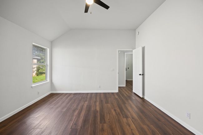 Empty room with ceiling fan, dark wood-style floors, and lofted ceiling | Image 17