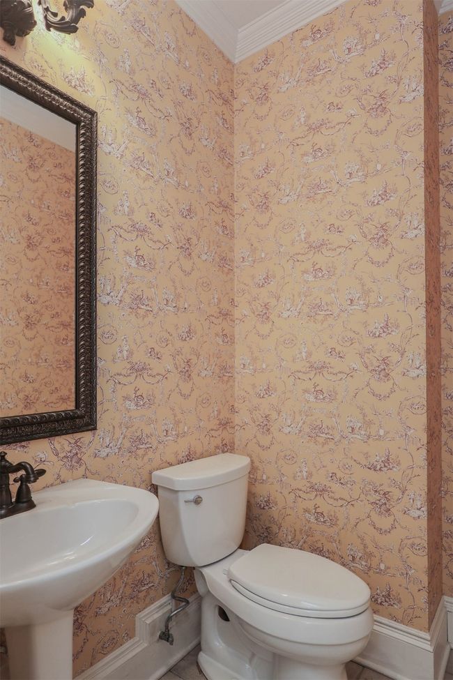 Half bath featuring wallpapered walls, crown molding, toilet, and a sink | Image 17