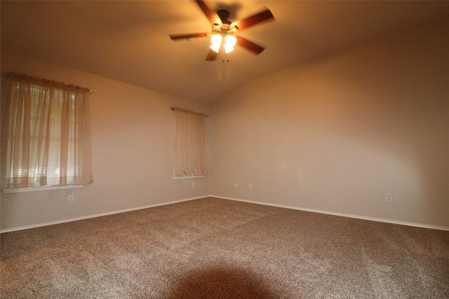 Unfurnished room featuring dark carpet, ceiling fan, and lofted ceiling | Image 20