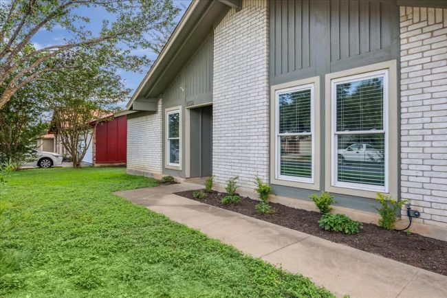 Entrance to property featuring brick siding, a yard, and board and batten siding | Image 4