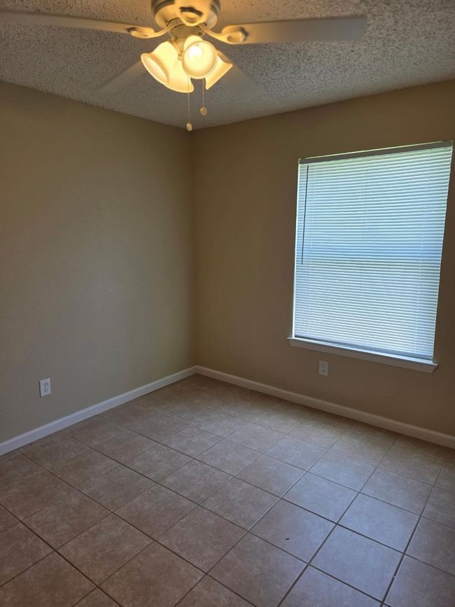 Tiled empty room featuring ceiling fan and a textured ceiling | Image 10