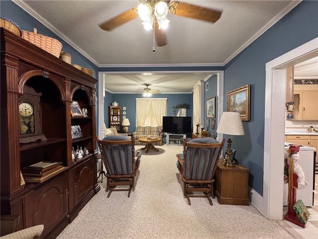 Carpeted living room with a ceiling fan and ornamental molding | Image 10
