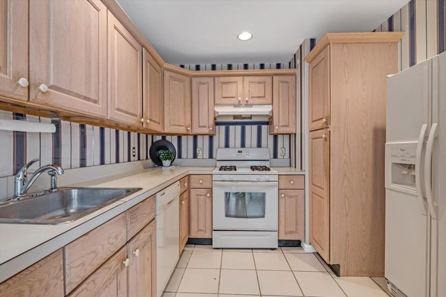 Kitchen featuring light brown cabinetry, white appliances, light tile patterned floors, under cabinet range hood, and recessed lighting | Image 8