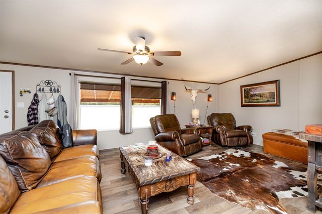 Living area with vaulted ceiling, a ceiling fan, crown molding, and wood finished floors | Image 5