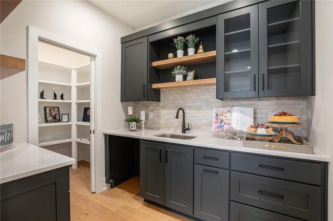 Indoor wet bar with light wood-style flooring and tasteful backsplash | Image 13