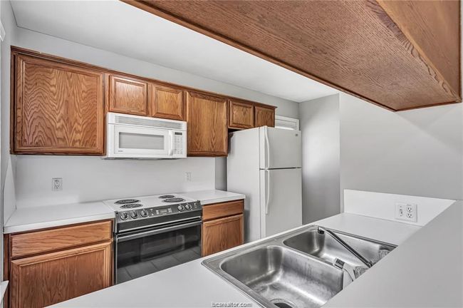 Kitchen featuring white appliances, light countertops, and brown cabinets | Image 7