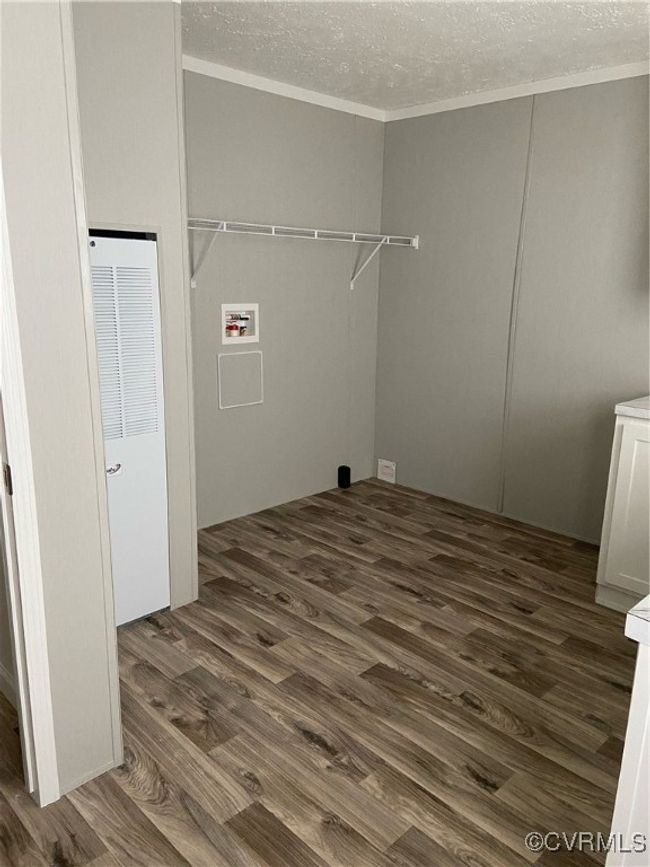 Clothes washing area featuring dark wood-type flooring, a textured ceiling, and hookup for a washing machine | Image 5