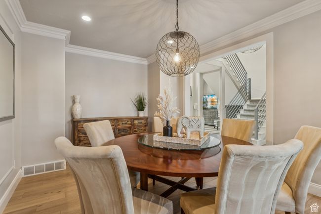 Dining space featuring light wood-type flooring, stairs, crown molding, and recessed lighting | Image 8