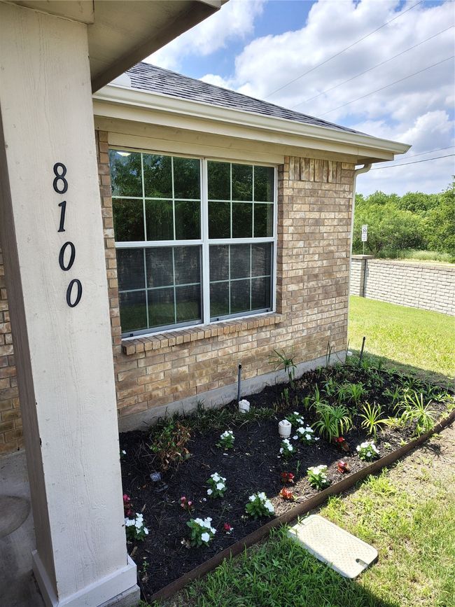 Exterior view of brick siding, a downspout, gutters, and a shingled roof | Image 4