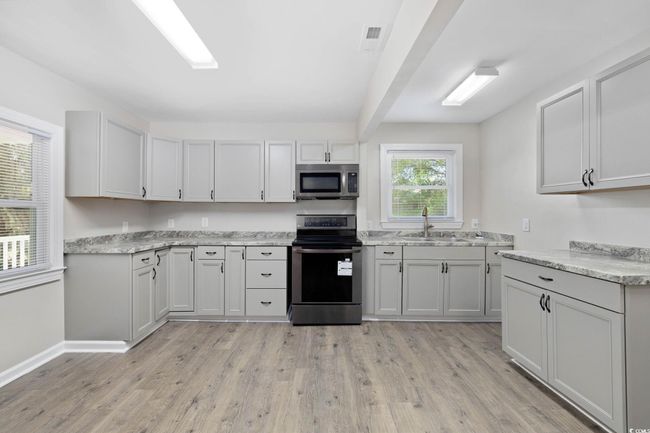 Kitchen with stainless steel appliances, a sink, light wood-style flooring, baseboards, and light stone counters | Image 19