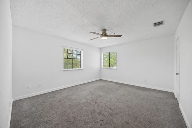 Carpeted spare room featuring a textured ceiling, a ceiling fan, baseboards, and visible vents | Image 16
