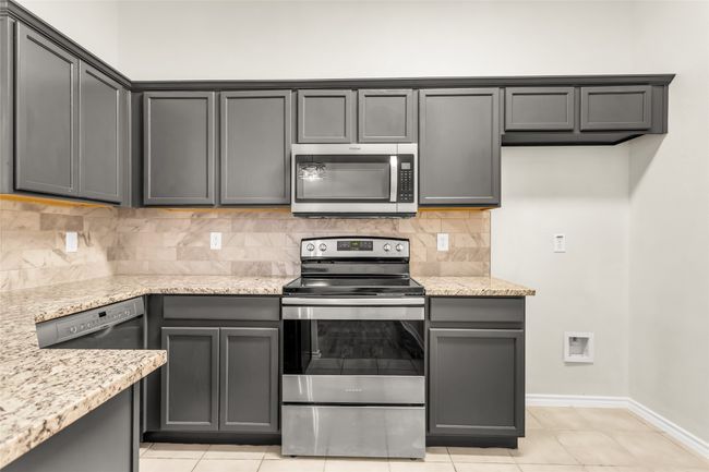 Kitchen featuring stainless steel appliances, light stone countertops, and decorative backsplash | Image 8