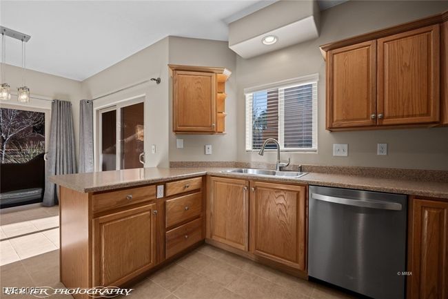 Kitchen with light tile patterned flooring, a peninsula, dishwasher, a sink, and brown cabinetry | Image 14