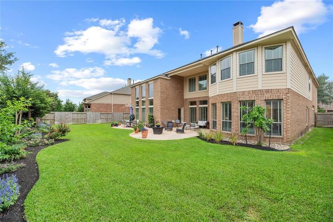 Well-manicured landscape along fence creates an inviting backyard scene. | Image 44