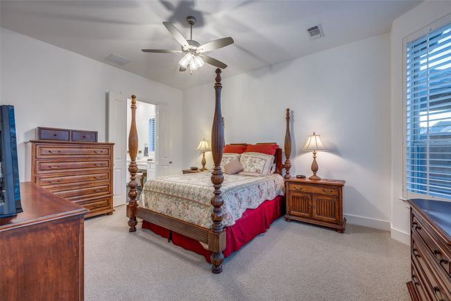 Carpeted bedroom featuring baseboards, a ceiling fan, visible vents, and ensuite bath | Image 12