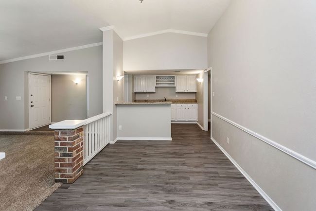 Wet bar room featuring carpet floors, vaulted ceiling, ornamental molding, a ceiling fan, and a chandelier | Image 11