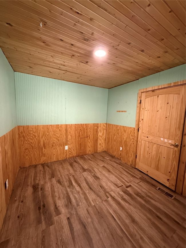 Unfurnished room with wood ceiling, wooden walls, and wood finished floors | Image 25