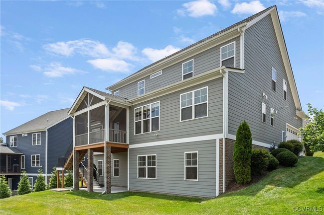 Rear view of house with brick siding, a sunroom, a yard, stairs, and a patio area | Image 45