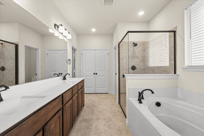 Full bathroom featuring a stall shower, a bath, and double vanity | Image 16