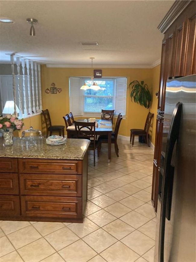 Kitchen with ornamental molding, decorative light fixtures, a notable chandelier, light stone countertops, and refrigerator | Image 18