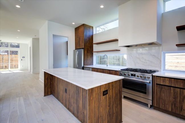 Gorgeous walnut cabinetry, high end Bosch appliances and quartz counters/backsplash. The enclosable laundry room is located to the left of the refrigerator. SEE VIRTUAL TOUR LINK WITH INTERACTIVE FLOOR PLAN AND 3D WALK THRU. | Image 10
