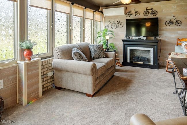 Carpeted living room with a fireplace, an AC wall unit, and a ceiling fan | Image 26