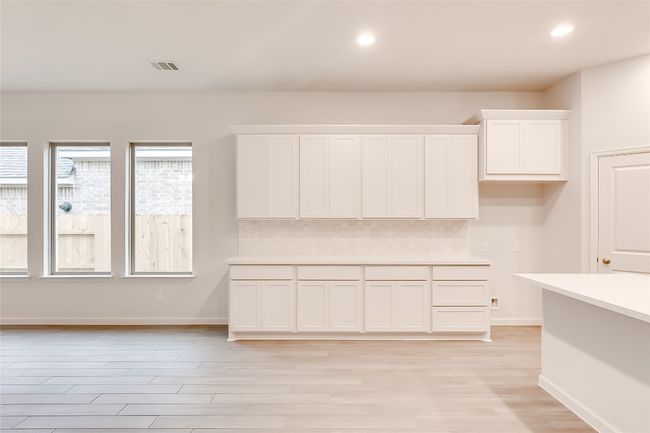 Kitchen featuring light countertops, white cabinetry, decorative backsplash, light wood-style flooring, and recessed lighting | Image 14