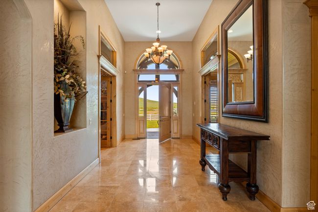 Foyer entrance featuring a textured wall, a chandelier, and baseboards | Image 20