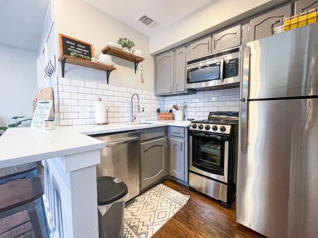 Kitchen featuring visible vents, gray cabinets, appliances with stainless steel finishes, and a sink | Image 7