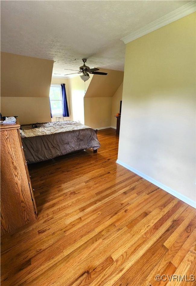 Bedroom featuring light wood-style floors, ornamental molding, a ceiling fan, and vaulted ceiling | Image 24